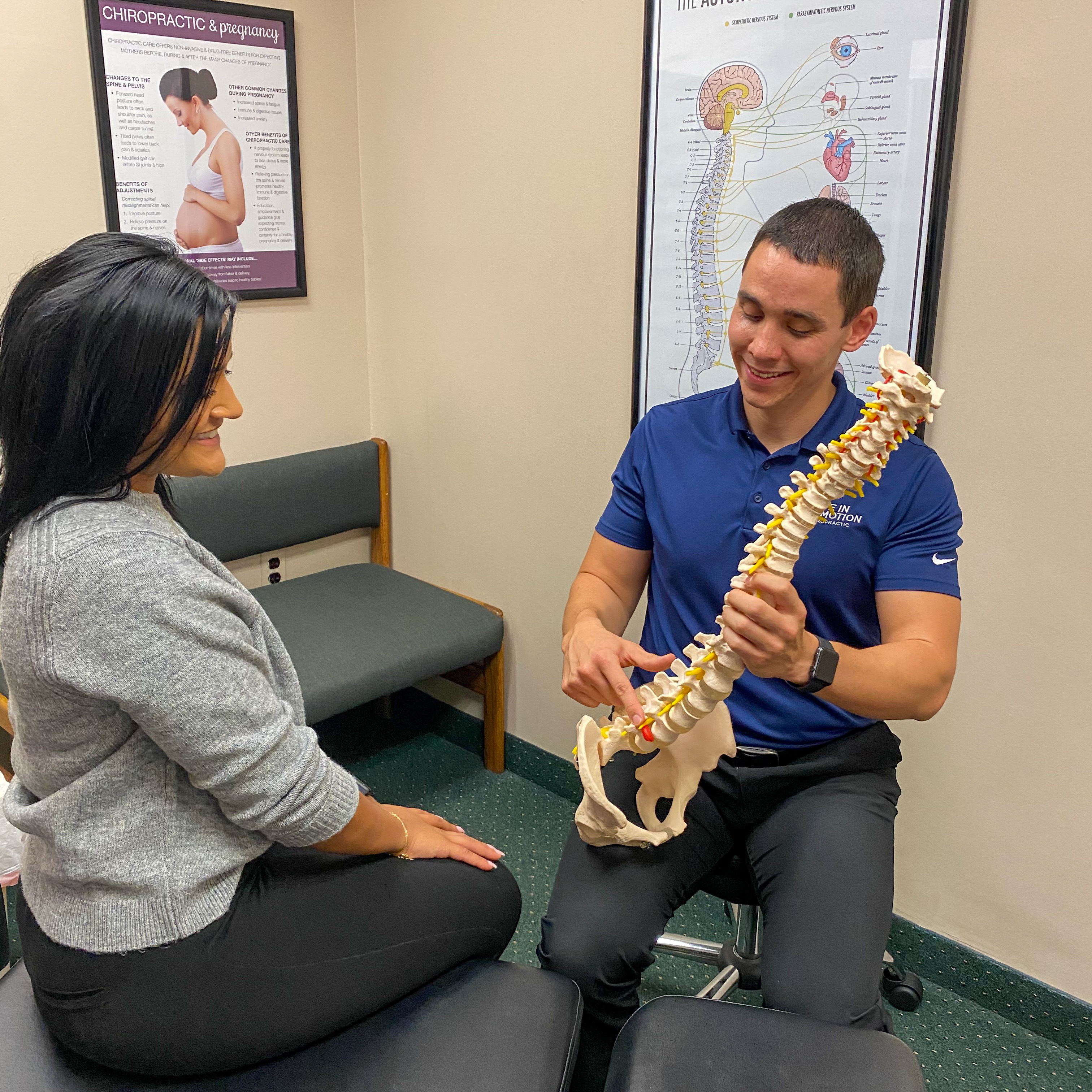 Dr. Travis Dockery explaining chiropractic findings to a patient using a spine model at Life in Motion Chiropractic in Livonia MI