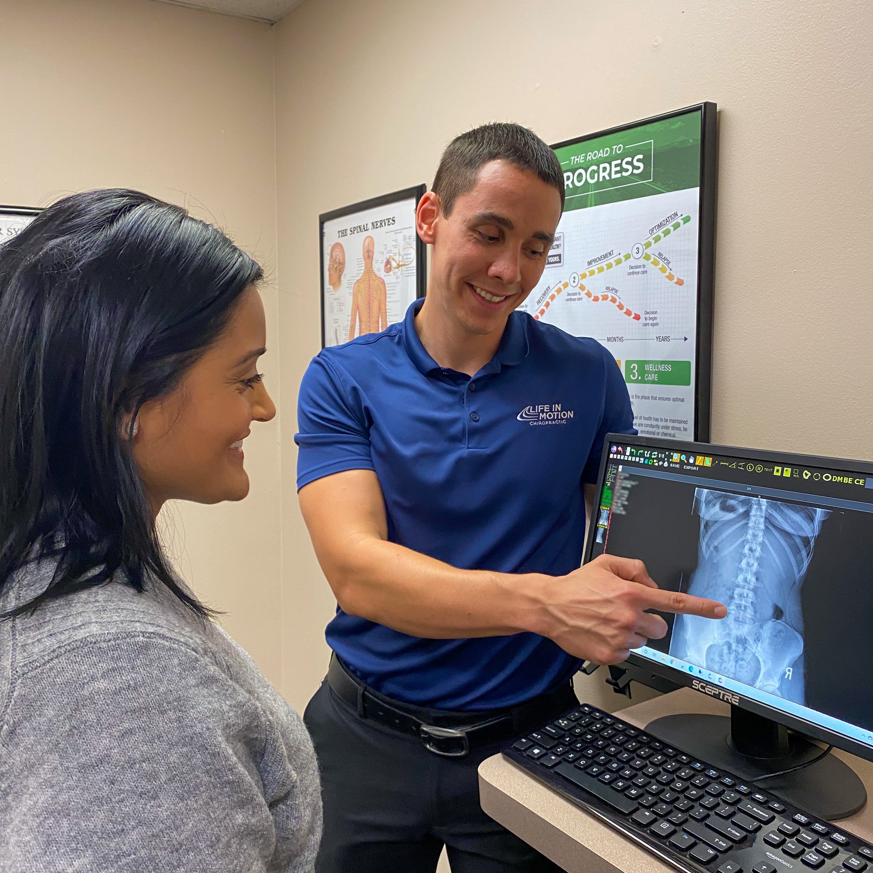 Dr. Travis Dockery reviewing digital X-rays with a patient at Life in Motion Chiropractic Livonia