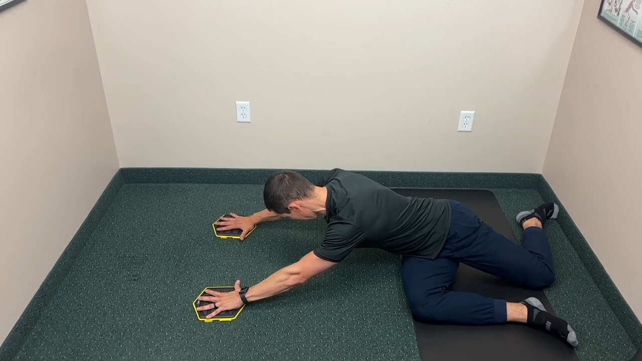 Dr. Dockery demonstrating the 9 Month High Oblique Shoulder Slider mid-movement — Life in Motion Chiropractic Livonia MI