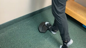 Chiropractor performing the ToePro warm-up calf and foot stretch on the ToePro device at a Livonia chiropractic clinic
